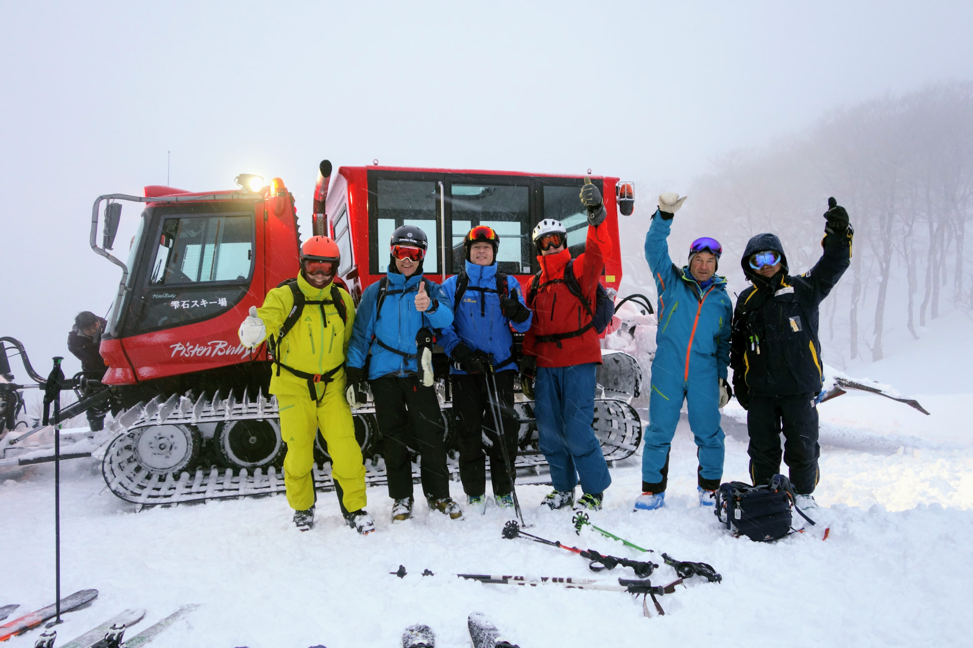 Gruppe von Skifahrern vor einer roten Pistenraupe im Nebel