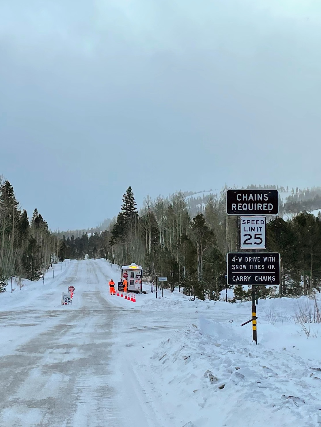 Kontrollposten an verschneiter Strasse mit Schild »Chains Required«