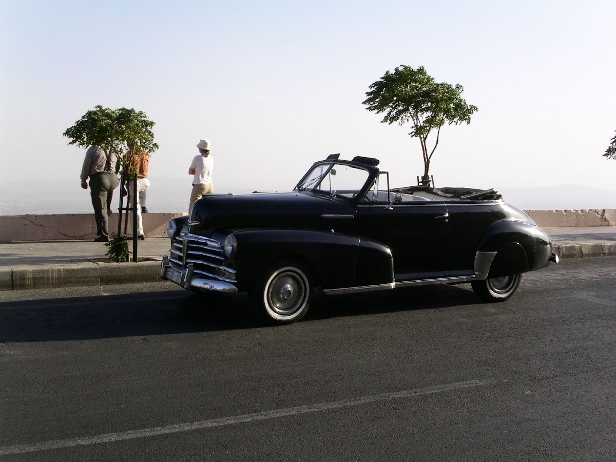 Schwarzes Oldtimer-Cabriolet auf einer Strasse in weiter Landschaft