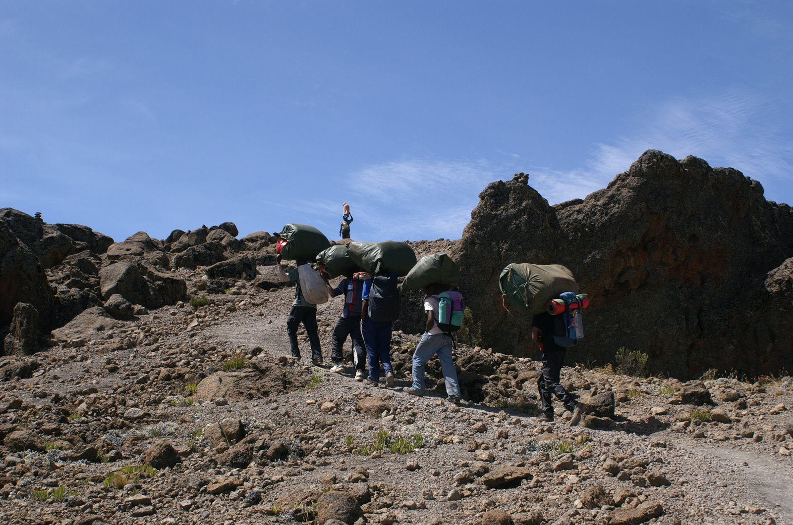 Träger mit schweren Lasten auf dem Kopf unterwegs am Kilimanjaro