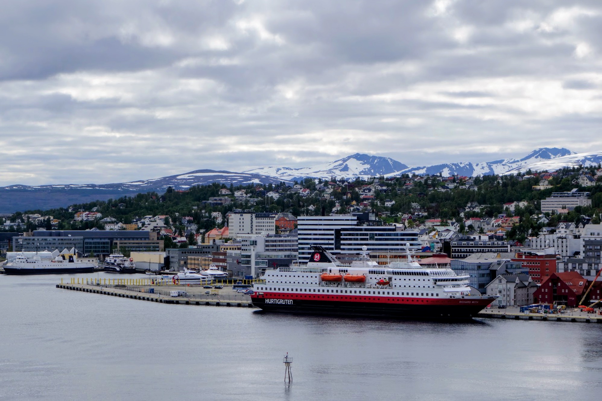 Hurtigruten-Schiff im Hafen von Tromsø vor schneebedeckten Bergen