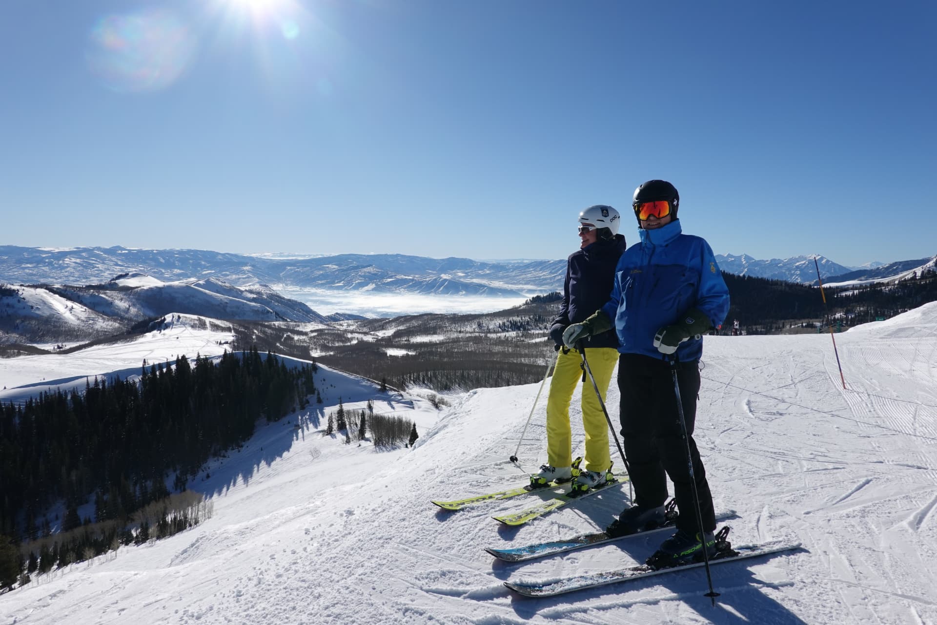 Zwei Skifahrer stehen auf einem Grat mit weitem Blick über verschneite Bergketten