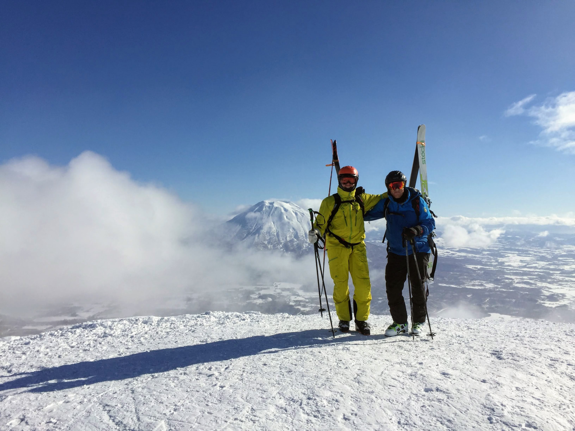 Zwei Skifahrer auf einem Gipfel mit dem Mount Yotei im Hintergrund