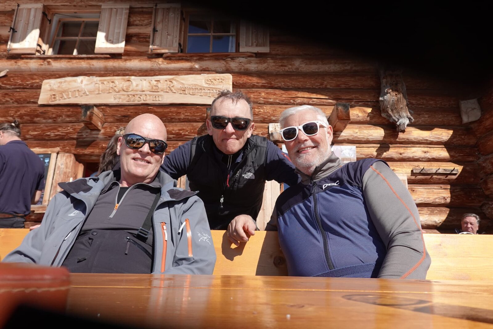 Drei Skifahrer auf der Sonnenterrasse einer Berghütte