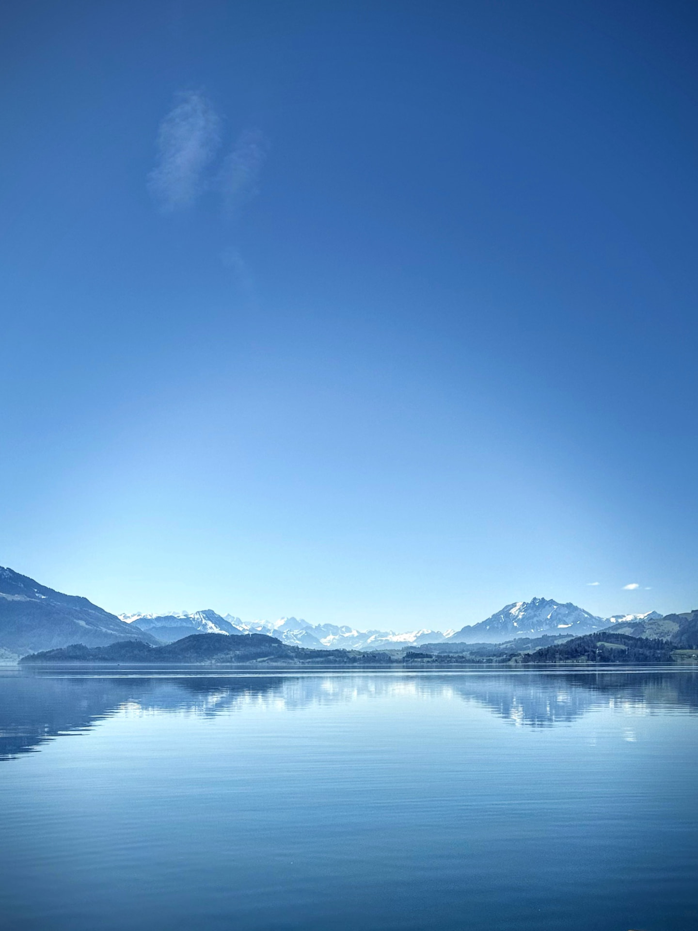 Blick über einen See auf schneebedeckte Berggipfel im Hintergrund