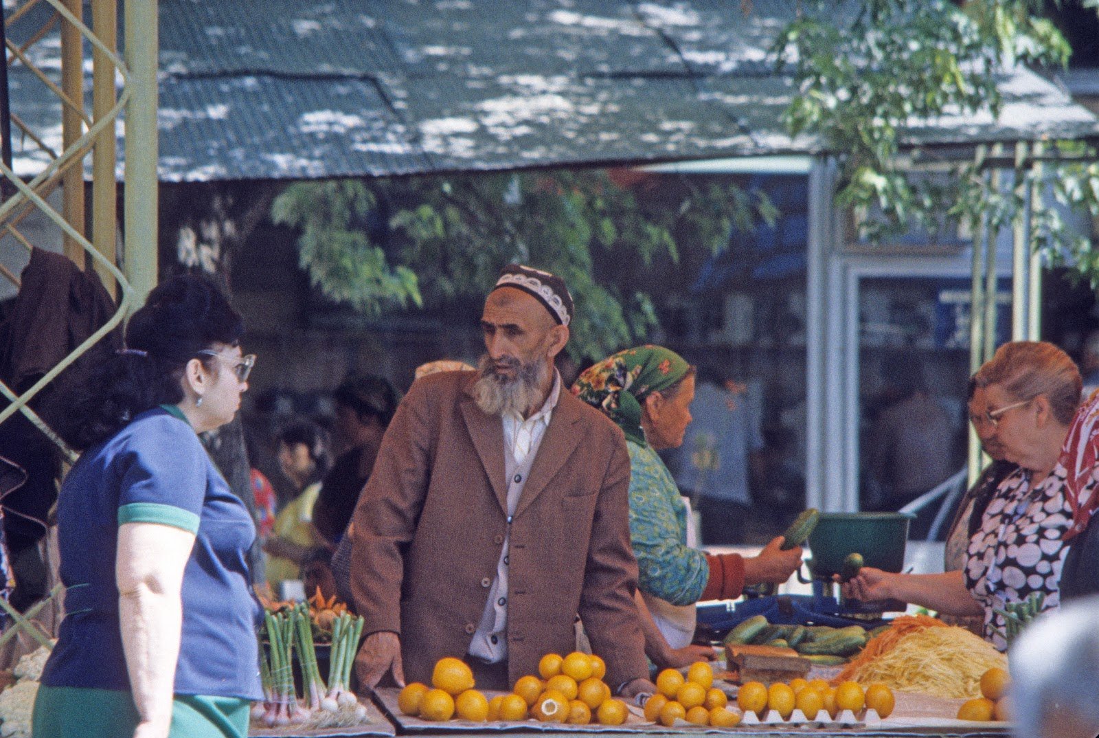 Marktstand mit Orangen, Verkäufer und Kundinnen auf einem Basar