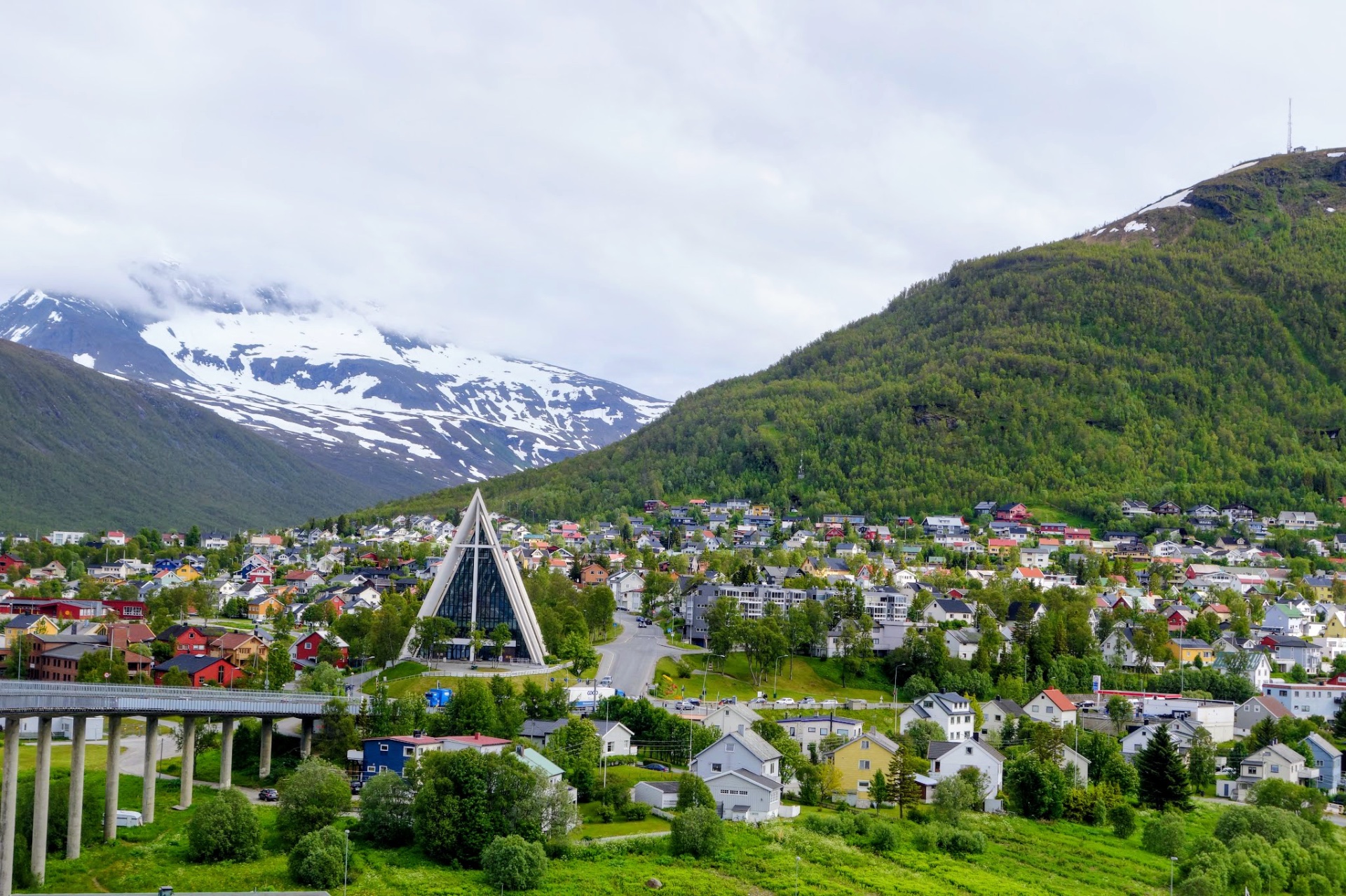 Die Eismeerkathedrale in Tromsø vor grünen Hängen und Schneebergen