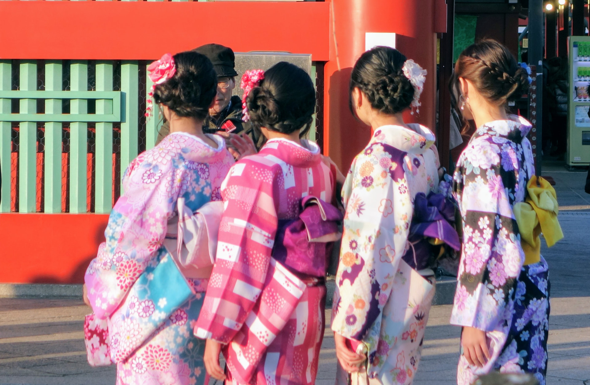 Vier Frauen in Kimonos vor einem roten Tempeltor in Tokio