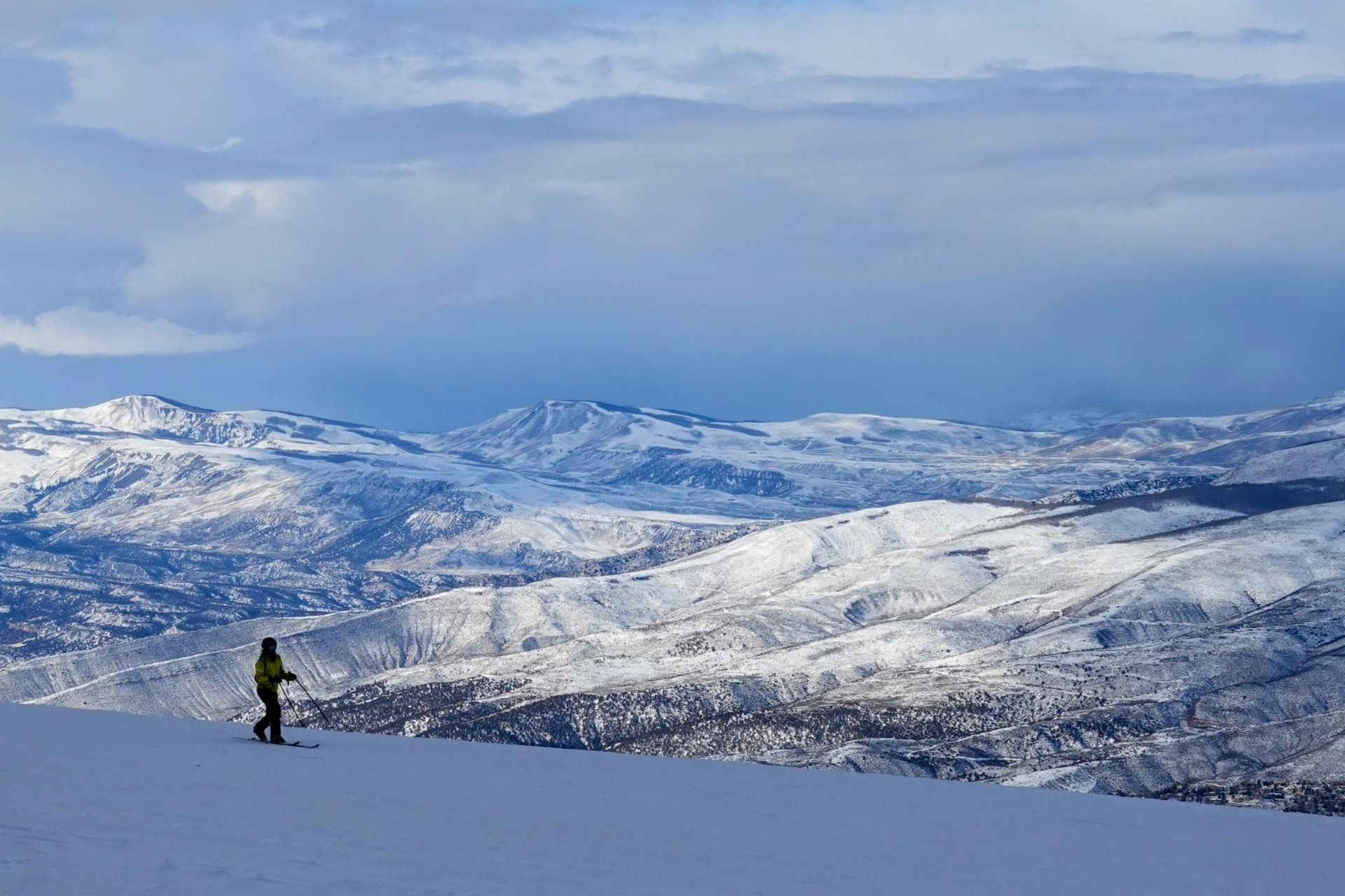 Einzelner Skifahrer vor weiter, verschneiter Hügellandschaft