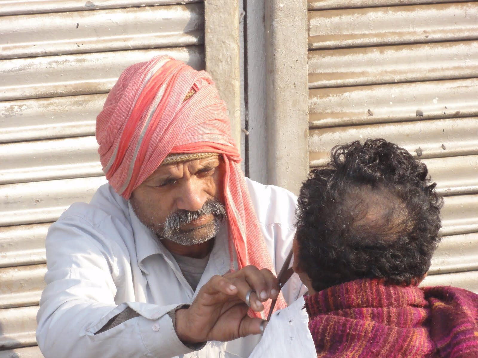 Strassenbarbier mit orangem Turban bei der Arbeit