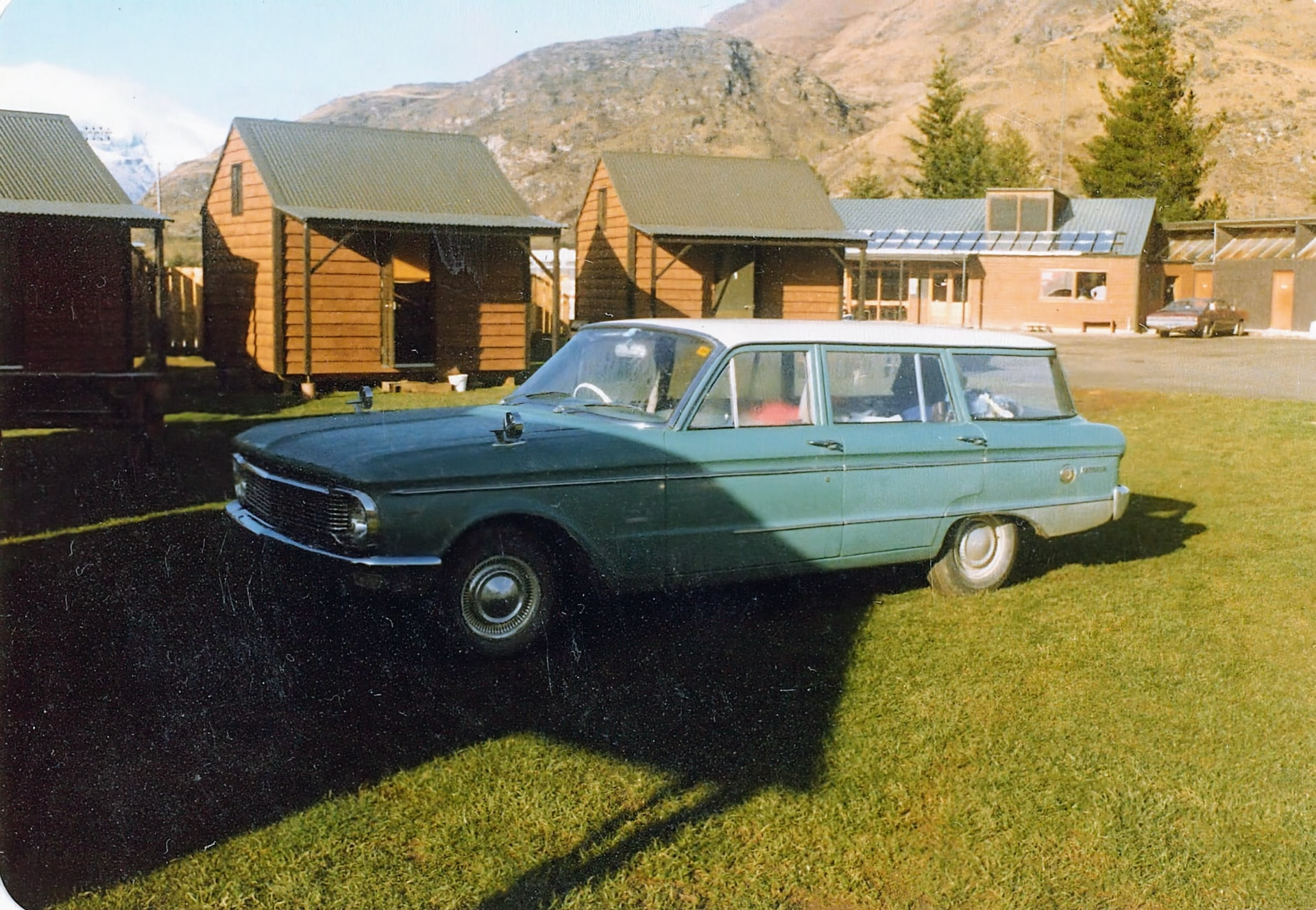 Alter grüner Holden Kombi vor Holzhütten in den neuseeländischen Bergen