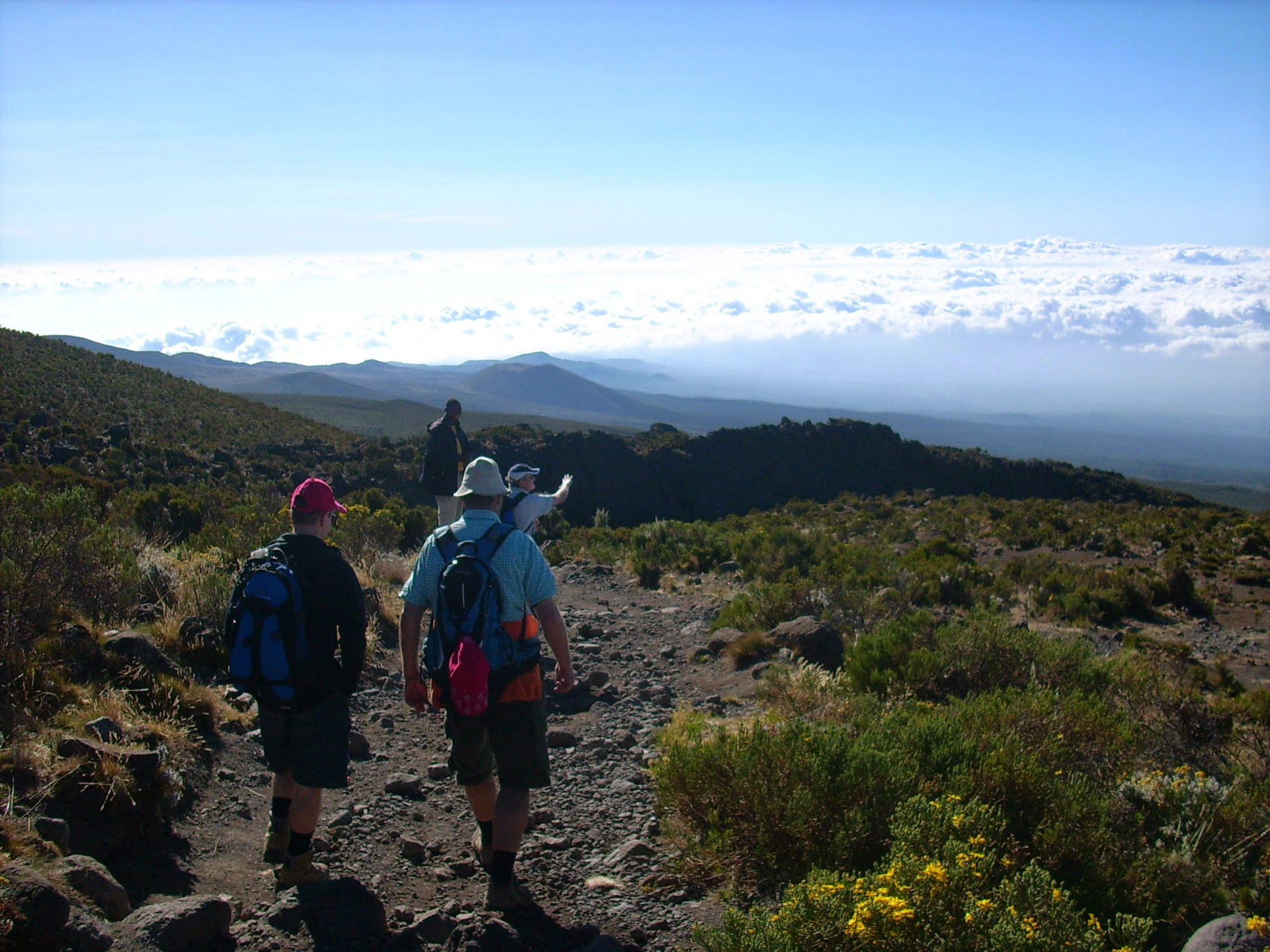 Wandergruppe auf steinigem Pfad über dem Wolkenmeer